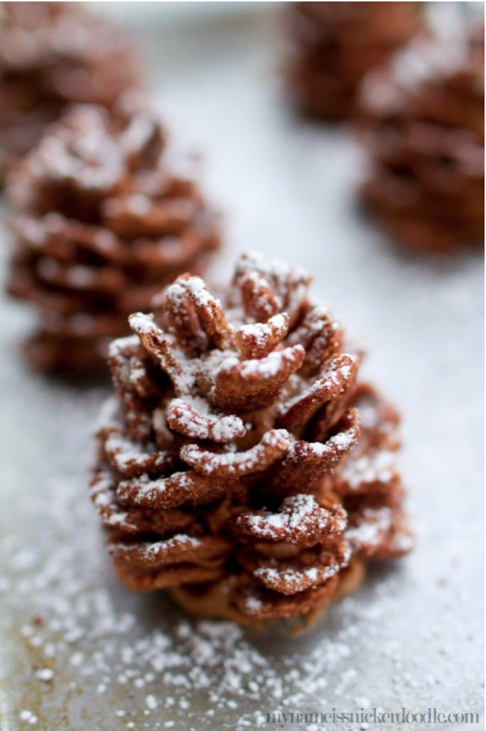Edible Chocolate Pinecones are such a holiday delight!  This no bake dessert recipe can be made ahead and only takes 30 minutes to create.  A creamy center made of peanut butter and chocolate spread and would you believe the outside is made of cereal?!  Imagine these on your Christmas dessert board or bringing them to your holiday party!