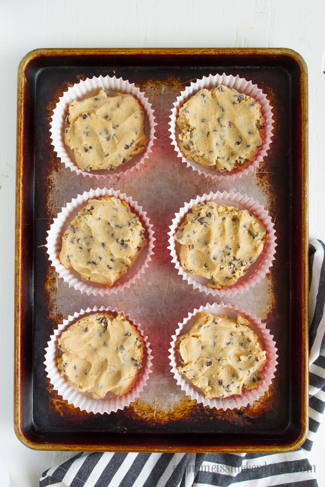 cookie dough in baking cups on a baking sheet.