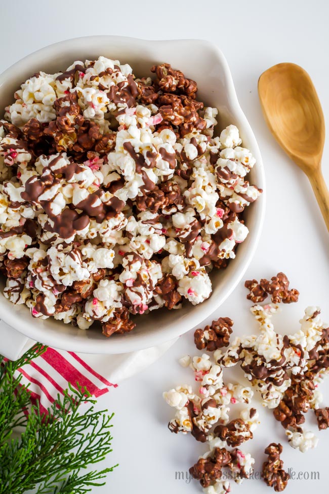 Peppermint Bark Popcorn drizzled with mint chocolate and peppermint candy in a bowl.  