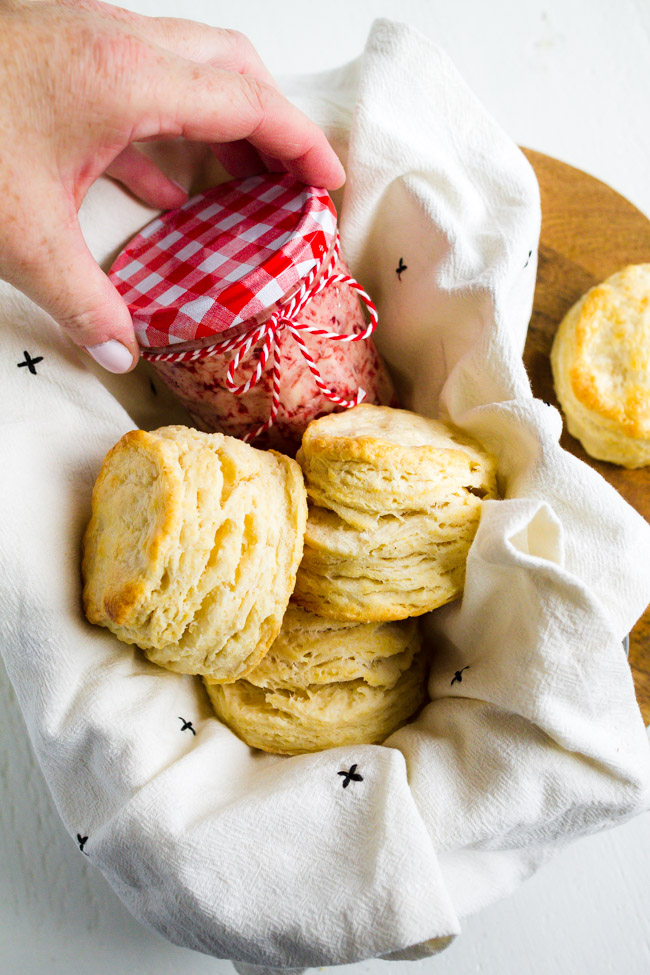 Raspberry Butter in a glass jar with a basket of biscuits
