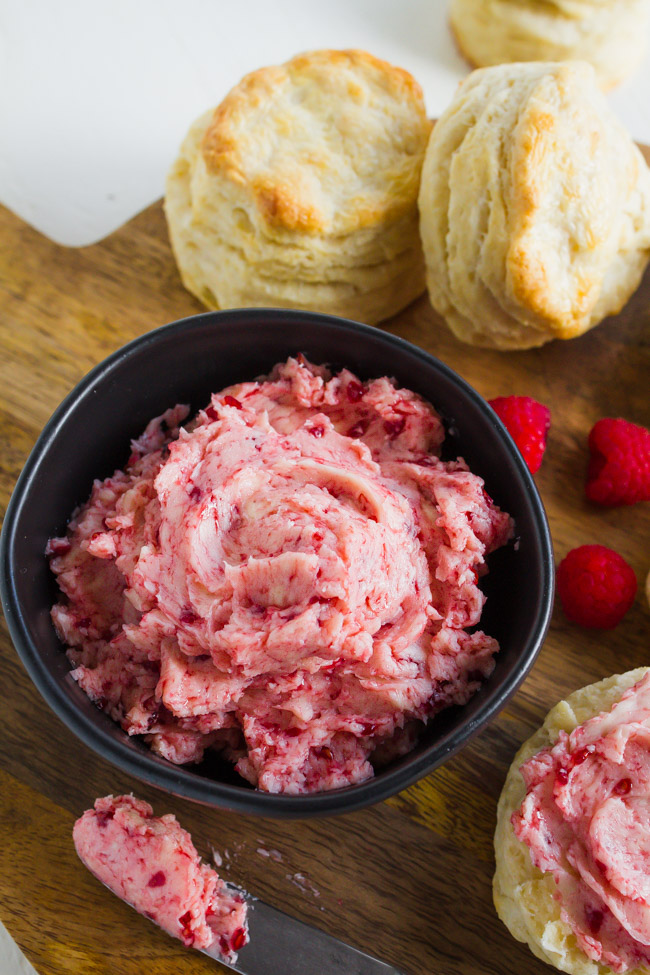 Raspberry Butter in a black bowl on a wood cutting board.