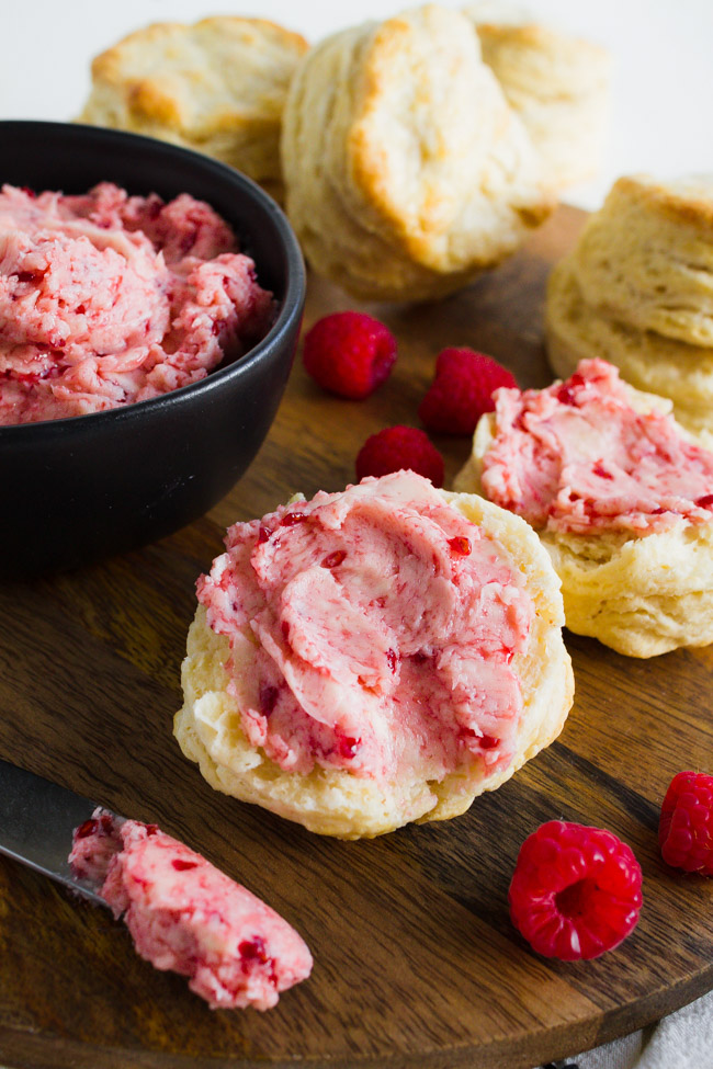 Raspberry butter slathered on top of homemade biscuits with a butter knife