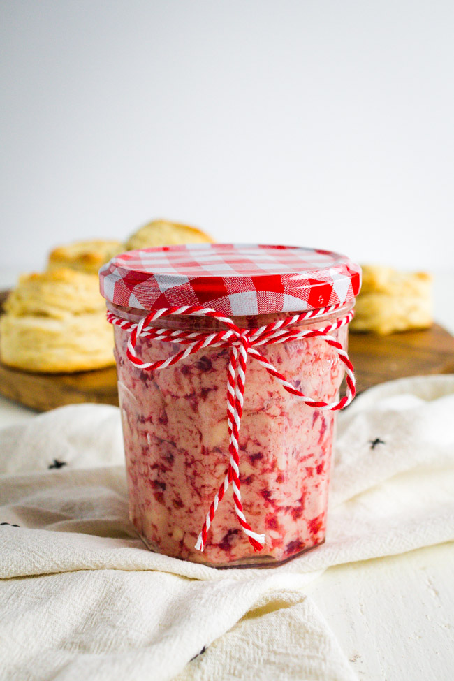 A glass jar full of raspberry butter tied with some bakers twine