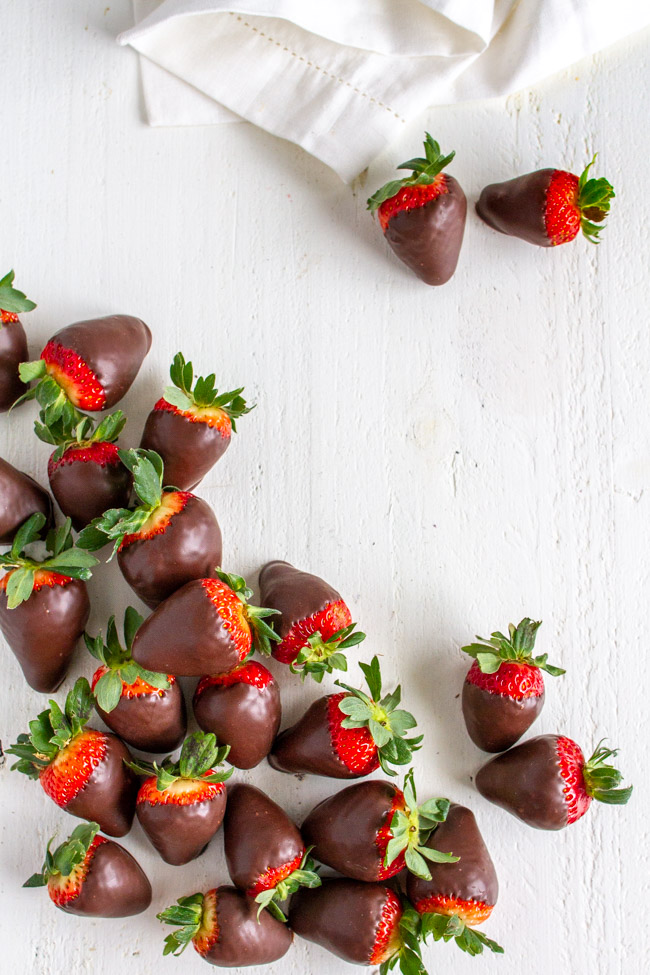 Chocolate covered strawberries in a pile on a white table