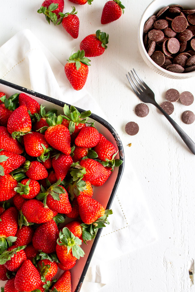 Strawberries on a platter with chocolate melts in a bowl