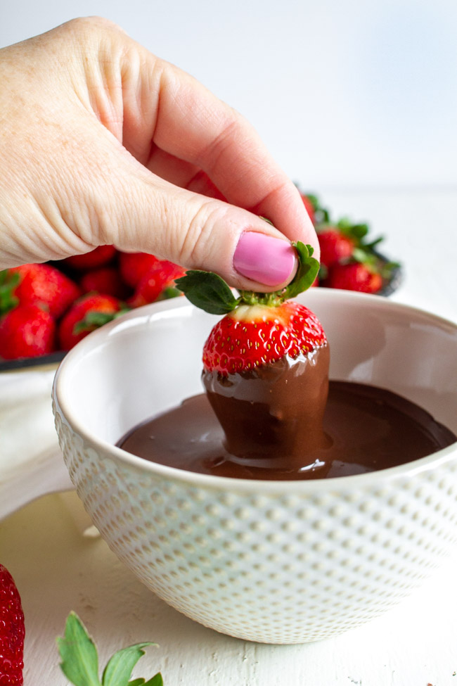 Dipping a strawberry into melted chocolate