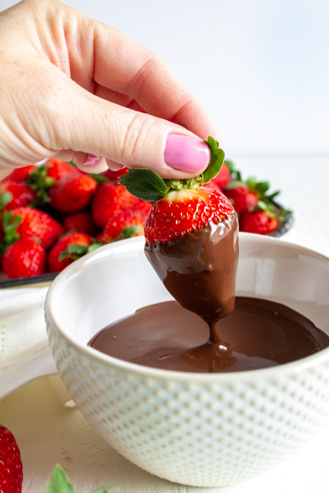 Strawberry being dipped into melted chocolate