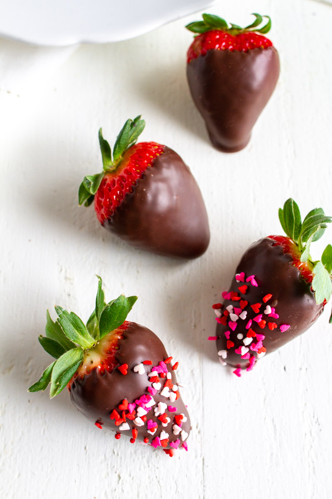 Chocolate dipped strawberries with valentine heart sprinkles on a table