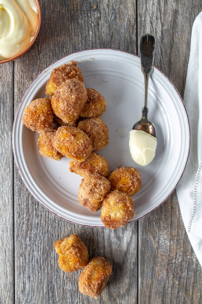 Cinnamon Sugar Pretzel Bites on a white plate with a spoonful of cream cheese frosting.