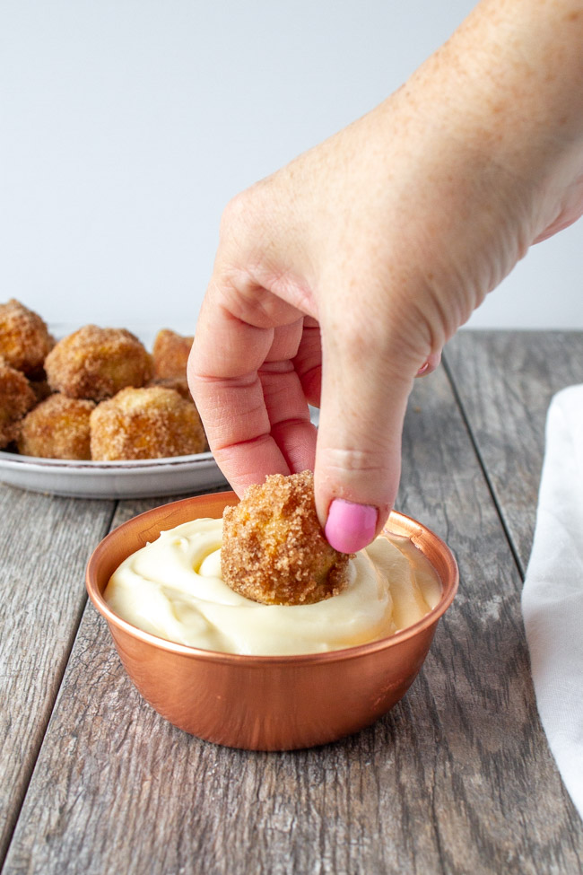 Dipping a cinnamon sugar pretzel into a bowl of cream cheese frosting.