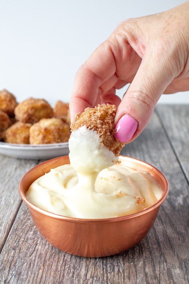 Dipping a cinnamon sugar pretzel bite into cream cheese frosting