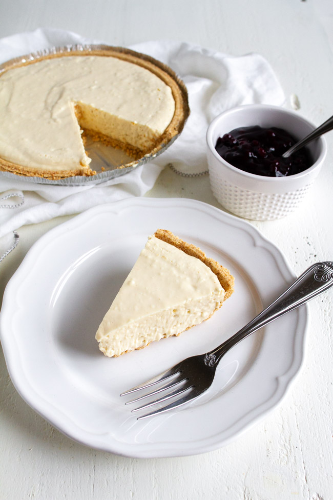 A plain slice of no bake cheesecake on a white plate with a fork.