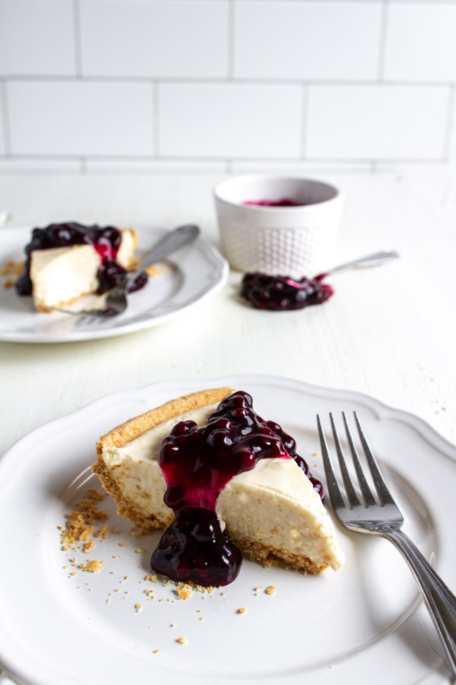 Slice of no bake cheesecake with blueberry topping on a white plate.
