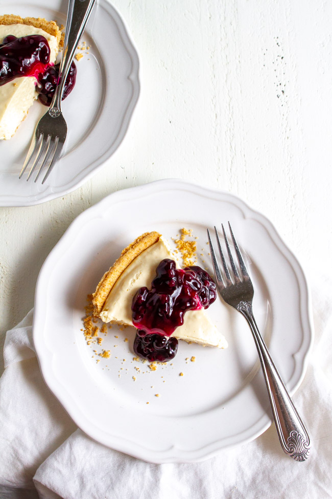 Two slices of blueberry no bake cheesecake on a white plates.  