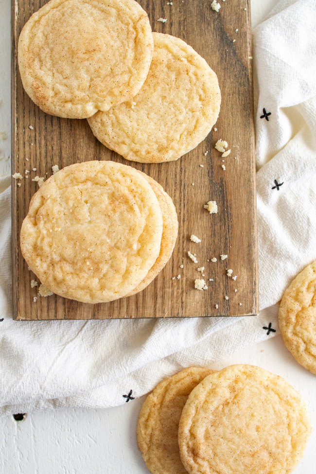 Snickerdoodles and crumbs on a wood tray.