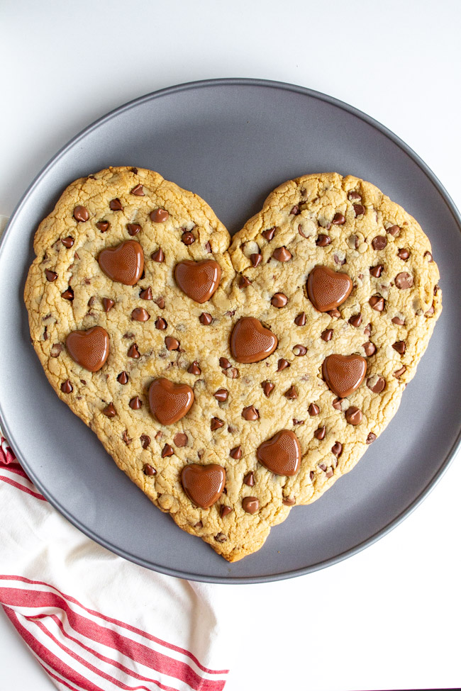 Heart Shaped Chocolate Chip Cookie with melted heart chocolates on a pizza pan.