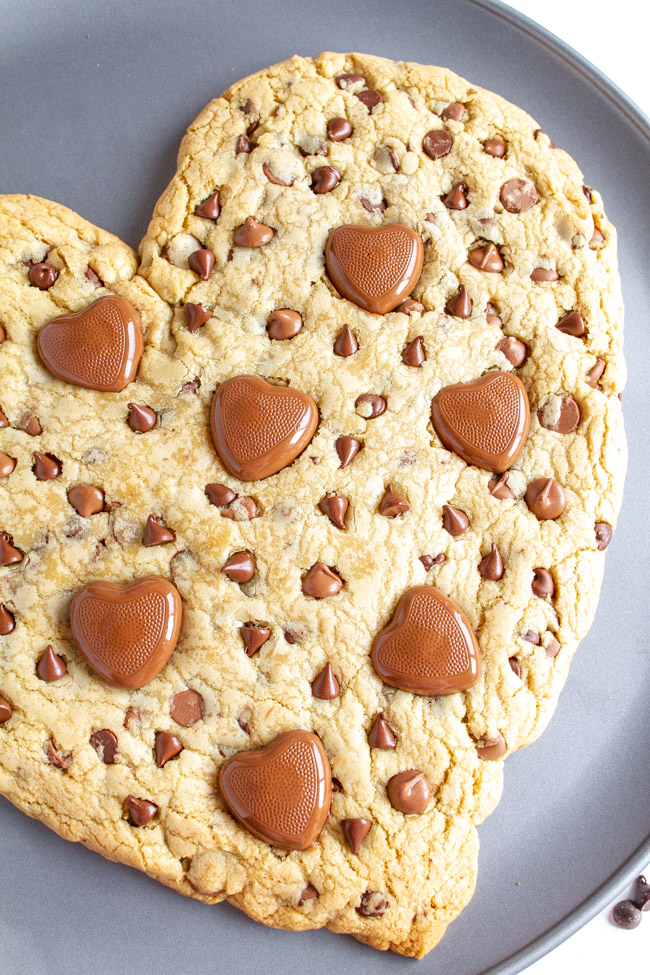 Close up of a Heart Shaped Chocolate Chip Cookie with heart chocolates on a pizza pan.