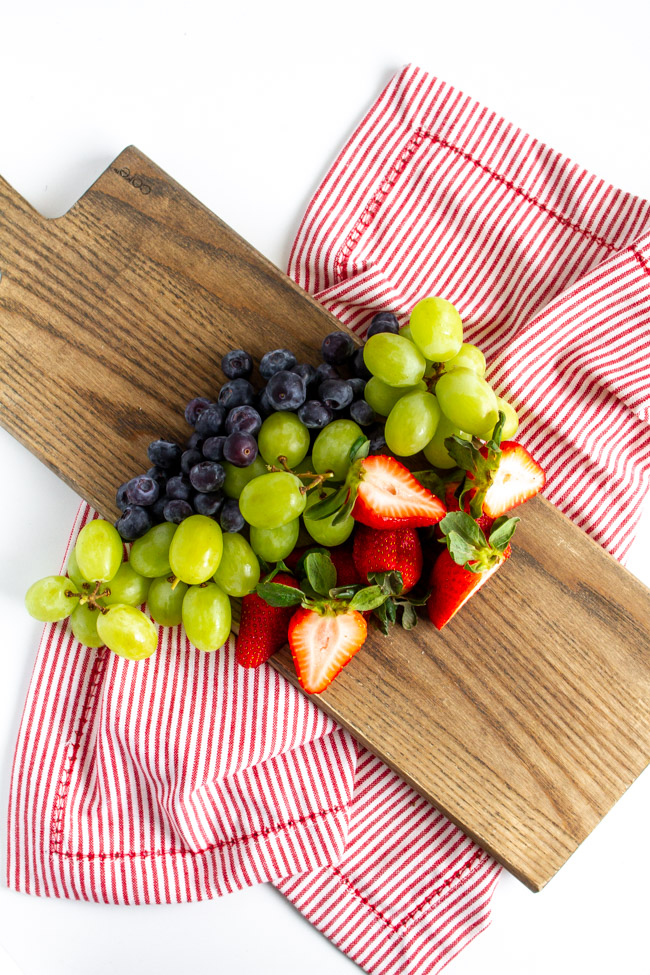 Strawberries, blueberries and grapes on a wood cutting board