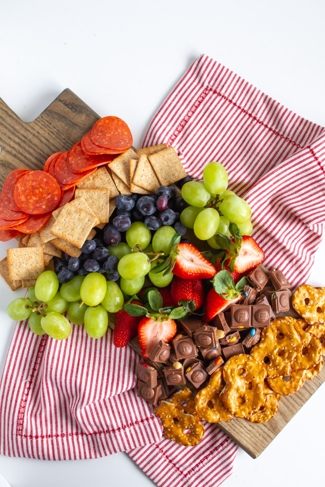 Chocolate, fruit, crackers and pepperoni on a wood cutting board