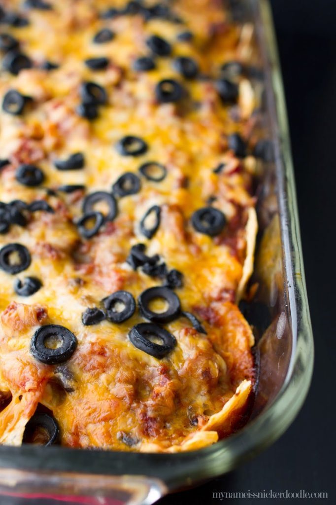 A 9x13 pan with Beef Enchilada Casserole topped with melted cheese and sliced black olives.