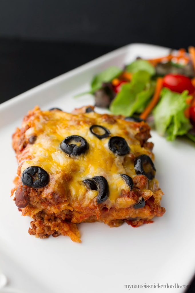 A slice of Beef Enchilada Casserole with cheese and sliced olives on top.