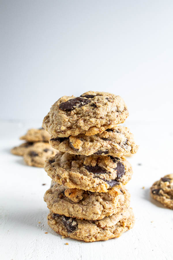 Oatmeal Chocolate Chip cookies stacked up on a white table with a few laying behind it.  