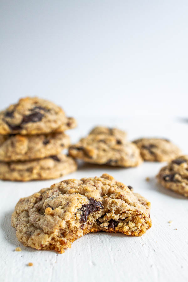 Oatmeal Chocolate Chip cookies with a bite taken out of one on a white table. 