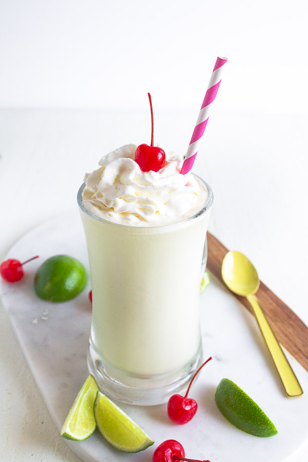 A clear glass mug with frozen key lime treat on a marble cutting board.