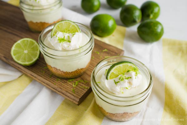 Two Mini Key Lime No Bake Cheesecakes in a small mason jars on a wooden board.