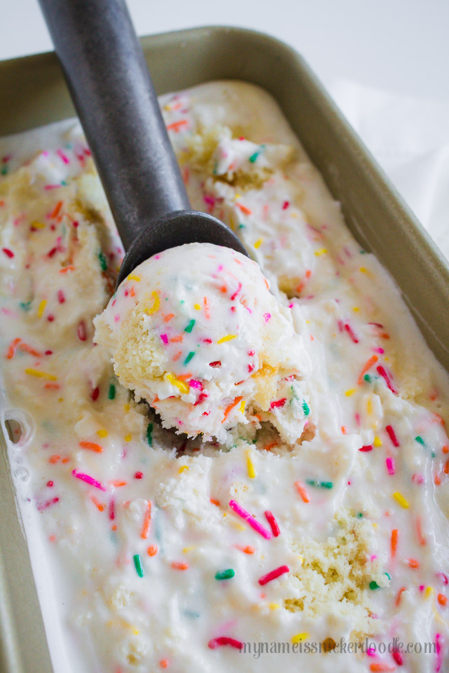 A scoop of birthday cake ice cream in a container.