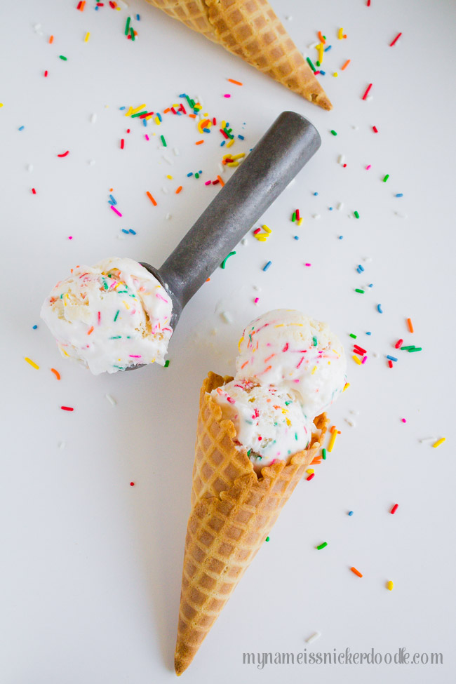 Waffle cone with two scoops of homemade birthday cake ice cream on a white table.