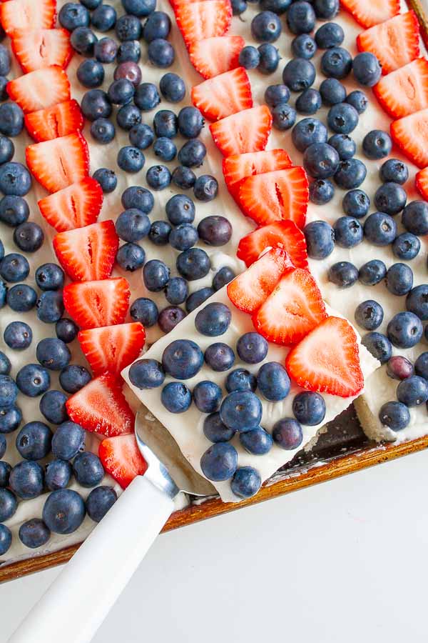 Patriotic Fruit Pizza with strawberries and blueberries in a cookie sheet being served.