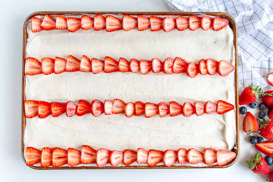 Sliced Strawberries on a sheet pan of frosted sugar cookie crust.  