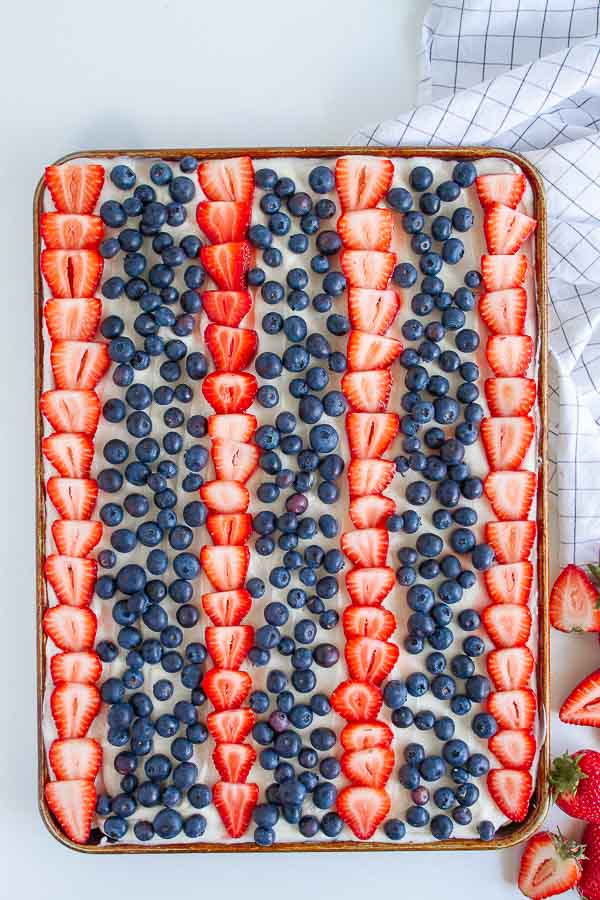 Patriotic Fruit Pizza with strawberries and blueberries in a cookie sheet.