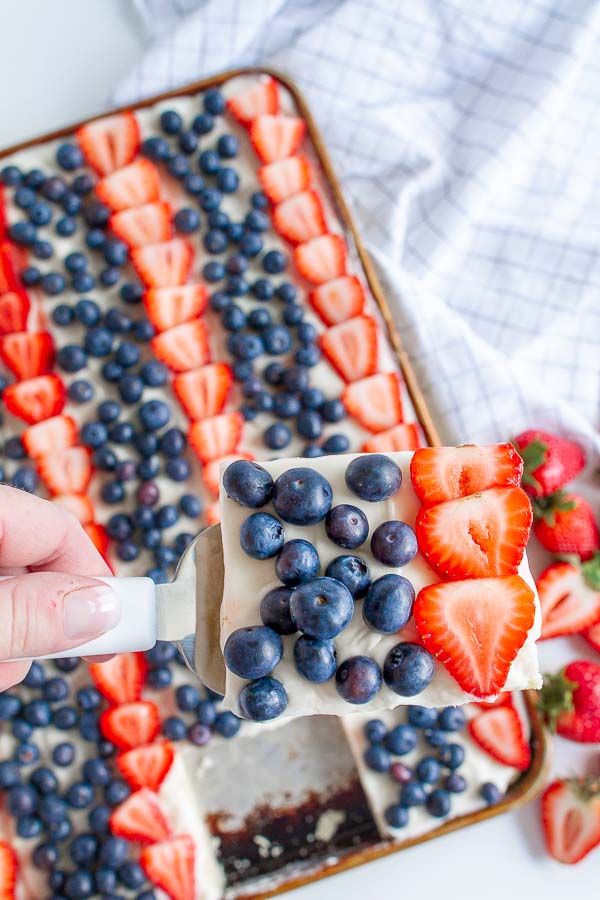 A spatula serving a square of fruit pizza.  