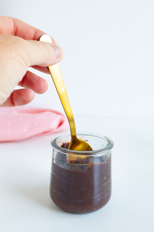 A gold spoon mixing a jar of chocolate chilled treats.