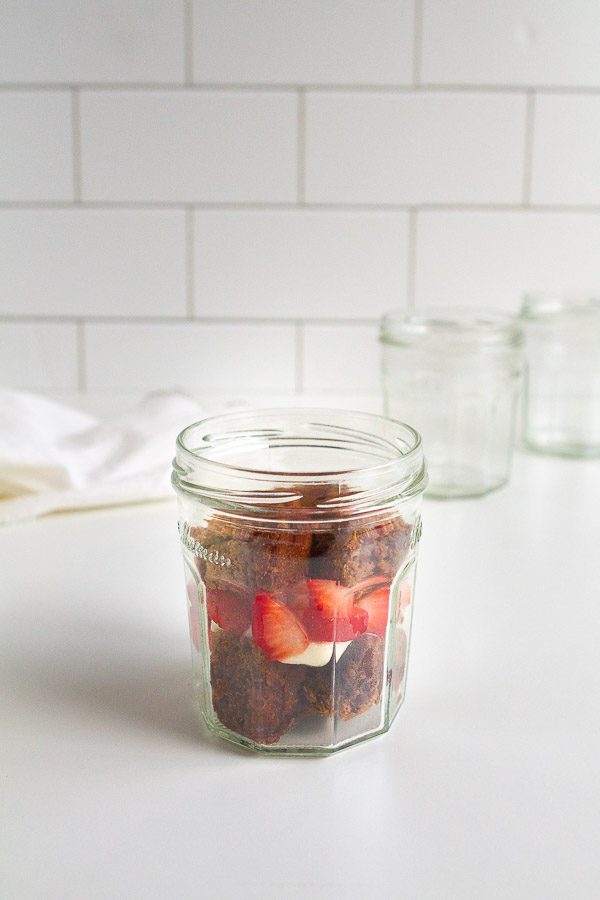 Brownie Strawberry Trifle in mini jam jars.  Layered with brownies, fresh strawberries and cream cheese frosting.  