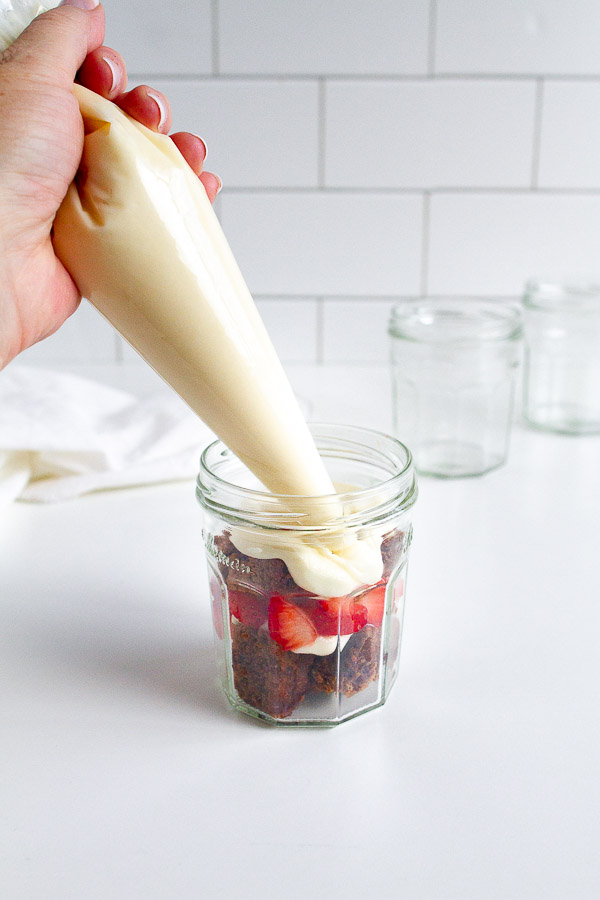 Brownie Strawberry Trifle in mini jam jars.  Layered with brownies, fresh strawberries and cream cheese frosting.  