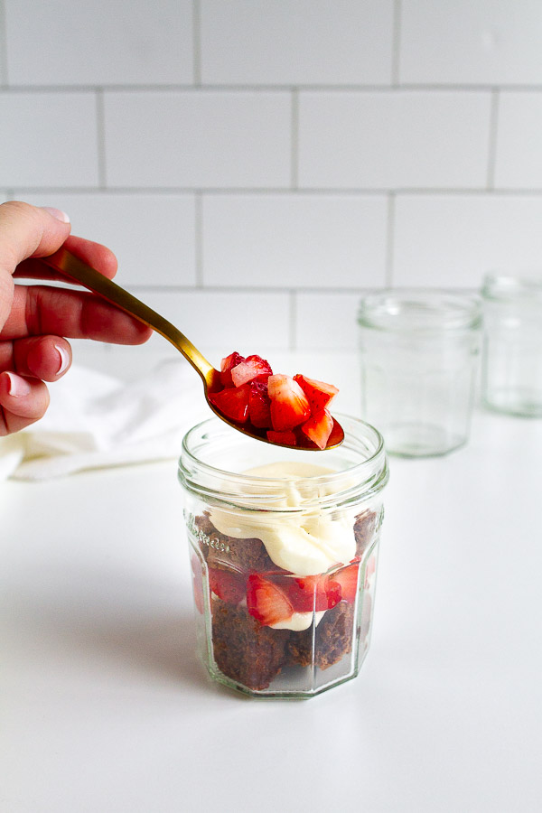 Brownie Strawberry Trifle in mini jam jars.  Layered with brownies, fresh strawberries and cream cheese frosting.  