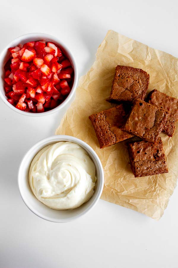 Brownie Strawberry Trifle in mini jam jars.  Layered with brownies, fresh strawberries and cream cheese frosting.  