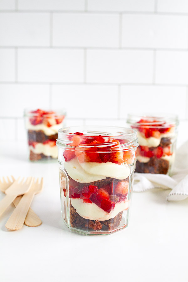 Brownie Strawberry Trifle in mini jam jars.  Layered with brownies, fresh strawberries and cream cheese frosting.  