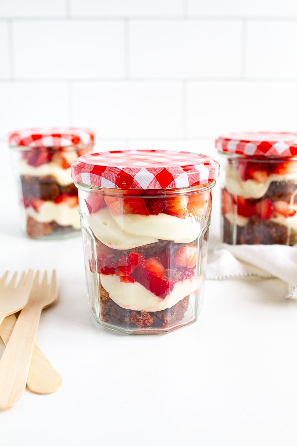 Brownie Strawberry Trifle in mini jam jars.  Layered with brownies, fresh strawberries and cream cheese frosting.  