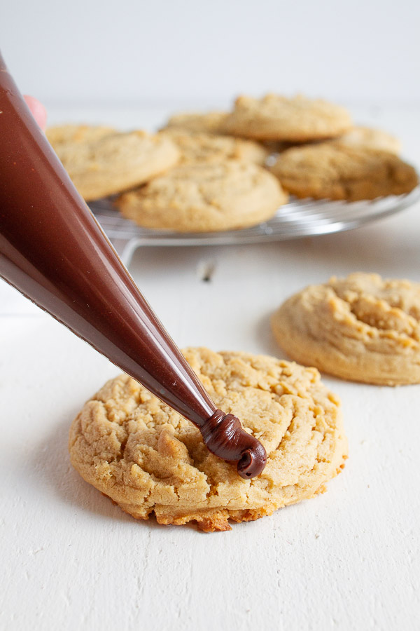 Butterfinger Peanut Butter Cookies are made with a tender chewy peanut butter cookie, drizzled with chocolate and topped with crushed Butterfinger candy!  