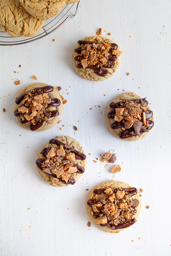 Butterfinger Peanut Butter Cookies are made with a tender chewy peanut butter cookie, drizzled with chocolate and topped with crushed Butterfinger candy!  