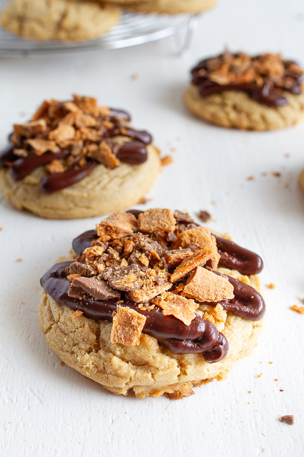 Butterfinger Peanut Butter Cookies are made with a tender chewy peanut butter cookie, drizzled with chocolate and topped with crushed Butterfinger candy!  