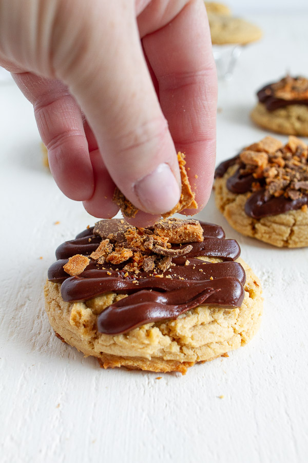 Butterfinger Peanut Butter Cookies are made with a tender chewy peanut butter cookie, drizzled with chocolate and topped with crushed Butterfinger candy!  