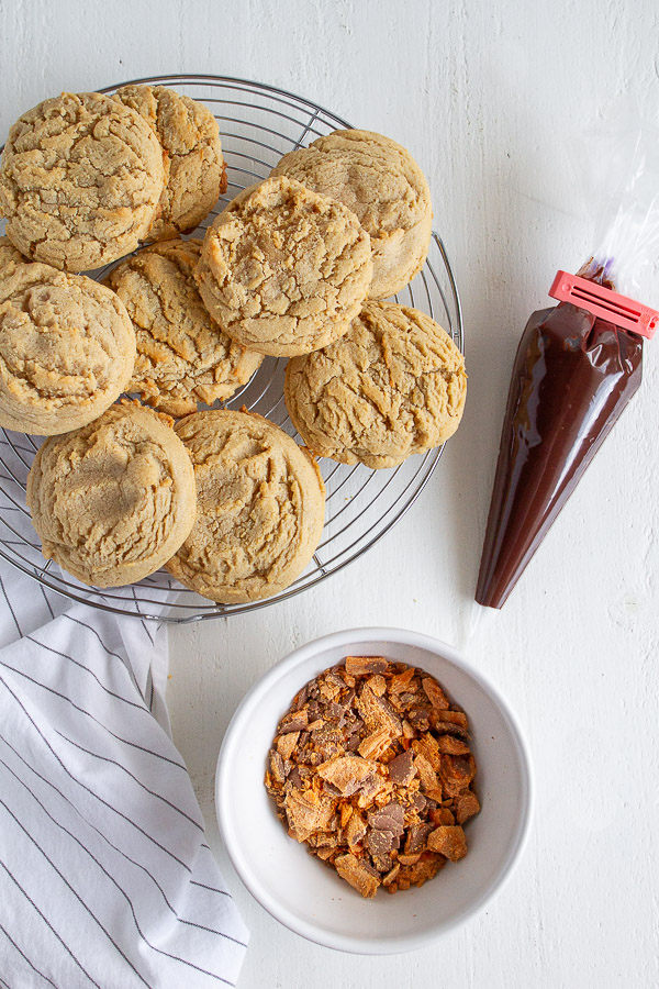 Butterfinger Peanut Butter Cookies are made with a tender chewy peanut butter cookie, drizzled with chocolate and topped with crushed Butterfinger candy!  