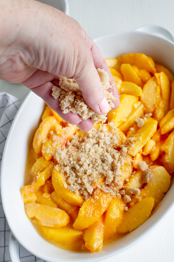 Sprinkle a generous amount of crisp topping onto sweetened sliced peaches.