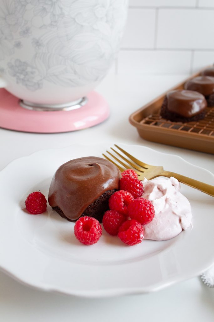 Mini frosted chocolate cakes with fresh raspberries and cream.