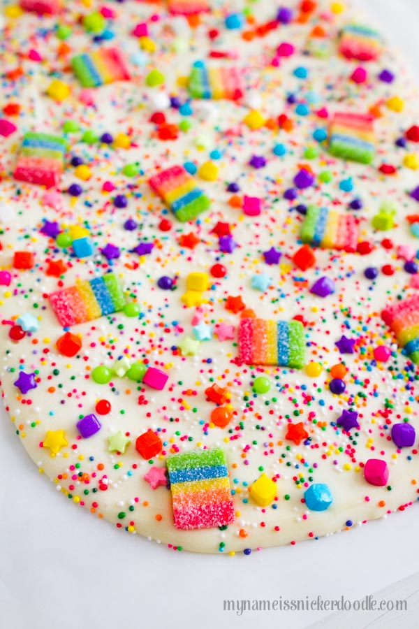 Rainbow sprinkles and gummies over melted white chocolate.